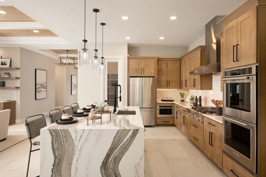 Kitchen in the Selby model at Monterey with a waterfall-edge quartz island, built-in ovens, and vent hood